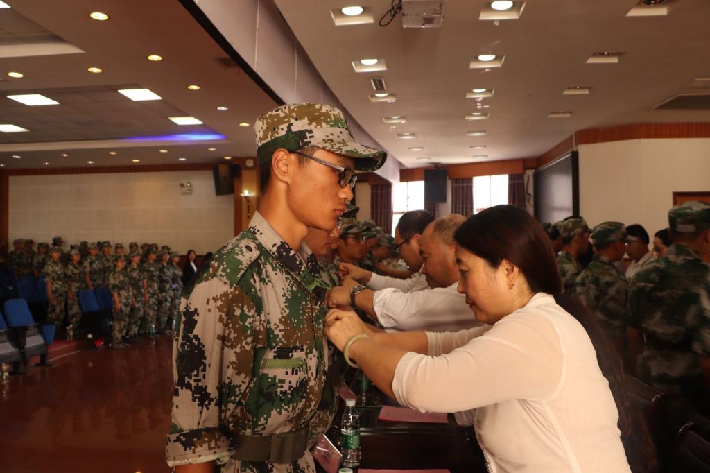 图为老师为新生佩戴校徽 张意摄